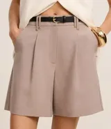 Short color visón de corte sastrero, tiro alto, con pliegues delanteros, trabillas y cinturón fino de cuero sintético.