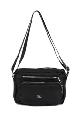 Bandolera negra de poliéster con múltiples bolsillos frontales con cierre metálico plateado y correa ajustable. Presenta un pequeño parche blanco con texto en la parte inferior central.