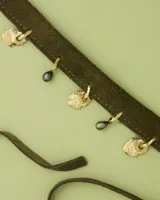 Gargantilla tipo choker de gamuza con dijes colgantes artesanales de metal y perlas naturales. Cuenta con tiras largas para atar y ajustar en la parte posterior.