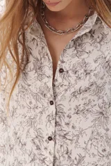Camisa de corte holgado con estampado floral en tonos marrones y blancos, cuello clásico y cierre frontal con botones.