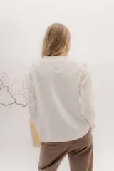 Remera de manga larga con escote a la base, color blanco, con un bordado central de dos líneas negras verticales en la parte delantera. La parte delantera es de lino y la espalda de algodón con spandex.