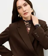 Blazer oversized estructurado marrón de corte cruzado con solapa amplia, bolsillos integrados y cuatro botones frontales.