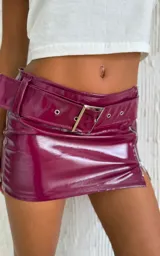 Minifalda de charol color borgoña, con cinturón con hebilla metálica y cierre lateral con cremallera.
