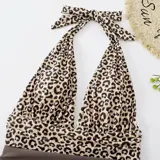 Malla entera combinada con parte superior lisa de color negro, escote halter cruzado y corpiño triangular con copas desmontables. Parte inferior de tiro alto con estampado animal print tipo leopardo.