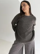 Sweater de punto color gris con cuello redondo, mangas largas y terminaciones con detalle de pespunte en color crudo en el cuello, puños y ruedo.