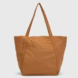 Bolso tipo tote de diseño amplio y ligero, confeccionado en tela técnica de acabado mate. Presenta doble asa superior para llevar al hombro, bolsillo frontal abierto y logo de la marca sutilmente grabado en la parte superior.