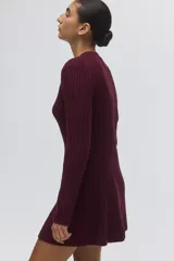 Vestido corto de punto acanalado color bordó, con cuello redondo, mangas largas y falda con leve vuelo. Presenta un diseño entallado con secciones de tejido menguado en la parte frontal y trasera.