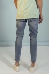 Pantalón de jean corte slim fit, color azul lavado, con cierre frontal y bolsillos laterales.