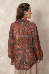 Blusa de gasa con estampado abstracto en tonos verdes y marrones, con detalles de hilos dorados. Presenta cuello camisero con escote en V, mangas largas con puños elásticos y un corte holgado.