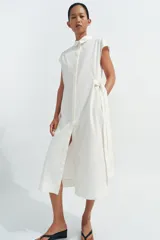 Vestido midi camisero de algodón color negro, con cuello solapa, sin mangas y cierre frontal con botones ocultos por solapa. Incluye cintura ajustable con tiras de lazada lateral en el mismo tejido.