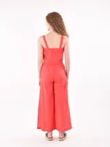 Pantalón de corte amplio y fluido, color rojo, con cintura elástica y cordón ajustable. Presenta aberturas laterales en el ruedo y bolsillos laterales.