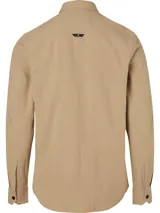 Camisa de manga larga color beige, confeccionada en tejido texturizado de algodón. Presenta cuello camisero, cierre frontal de botones y un bolsillo en el pecho con una insignia cuadrada negra con el logo 'CK' en blanco.