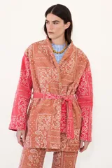 Kimono de jean con estampado tipo bandana en tonos rojizos y anaranjados, con forro interior de corderito blanco. Presenta un diseño de corte recto, mangas largas y cinturón del mismo tejido.