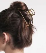 Pinza para el pelo dorada con forma de media luna y diseño geométrico.