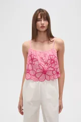 Top lencero de algodón color rosa claro, con tirantes finos y escote profundo. Presenta bordados florales grandes en color fucsia con detalles de mostacillas en el centro de las flores. El calce es holgado.