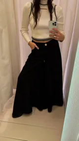 Pantalón palazzo negro de tiro alto con pinzas delanteras y bolsillos laterales.