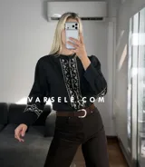 Camisa de manga larga color blanco con bordados geométricos en negro a lo largo de la botonadura frontal y en los puños. Presenta cuello mao y cierre frontal con botones.