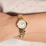 Reloj analógico Guess modelo Leena con caja redonda de acero inoxidable en tono dorado. La esfera blanca presenta un bisel interno decorado con cristales brillantes y marcadores de hora minimalistas. La correa es de acero inoxidable con un diseño de eslabones tipo brazalete.