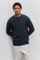 Sweater de tejido de punto acanalado en color marrón, con cuello redondo y ajuste holgado. Presenta un pequeño bordado distintivo en el pecho.