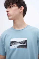 Remera blanca de algodón con cuello redondo y manga corta. Estampado fotográfico en el pecho con texto.