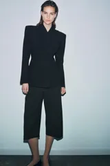 Blazer entallada de Zara Woman Collection, color negro, con escote en pico, manga larga con hombreras y cierre frontal con botones ocultos. Presenta bolsillos con solapa en el delantero y detalle de nervios marcados.