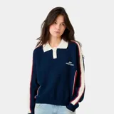 Buzo oversize azul marino con cuello polo color crema y cierre parcial. Presenta franjas rojas y crema en las mangas, con un diseño trenzado en las franjas crema. El logo de Eme Studios está bordado en el pecho.