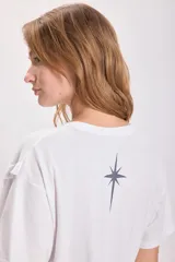 Remera blanca de algodón con cuello redondo y mangas cortas. Presenta un estampado de estrella en el frente.
