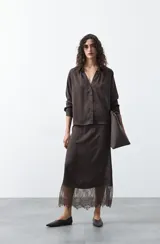 Falda midi negra de caída fluida con cintura elastizada y un amplio detalle de encaje negro en el bajo.