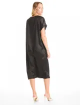 Vestido midi de satén negro con silueta holgada y fluida. Presenta escote en V profundo adornado con un delicado ribete de strass, mangas cortas amplias y una tabla central bajo el escote que aporta movimiento a la prenda.