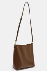 Bolso de hombro tipo saca en color marrón, con diseño minimalista y cierre de clip metálico. Incluye una correa de hombro con detalles troquelados en contraste y herrajes dorados.