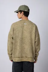 Buzo de cuello redondo con efecto de teñido artesanal acid wash. Presenta un corte oversize, mangas largas con puños acanalados y etiqueta pequeña en el puño izquierdo.