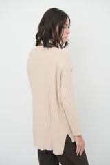 Polera de tejido de punto acanalado en color beige, con cuello alto, manga larga y diseño de corte recto con aberturas laterales en el ruedo.