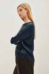 Sweater de punto en color azul oscuro, con cuello redondo y mangas largas. Presenta un diseño frontal completamente cubierto de lentejuelas brillantes en tonos azulados y verdosos.