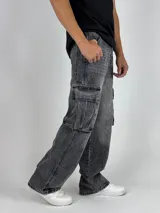 Pantalón de jean gris oscuro lavado, estilo cargo y corte baggy, con múltiples bolsillos laterales y calce holgado.