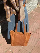 Cartera tipo tote de cuero color camel, con diseño estructurado, costuras decorativas laterales y doble asa superior para el hombro.