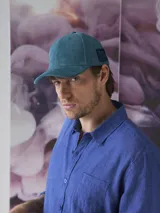 Gorra de pana color petróleo con visera curva y logo de la marca bordado en el lateral.