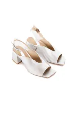 Sandalias de cuero vacuno metalizado en color plateado, con diseño minimalista, punta cuadrada abierta y capellada estilizada con abertura en V. Cuenta con tacón medio en bloque y tira slingback ajustable con hebilla metálica en el talón.