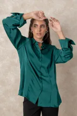 Camisa de seda con acabado satinado, de corte holgado y manga larga con puños anchos. Presenta cuello clásico y cierre frontal con botones al tono.
