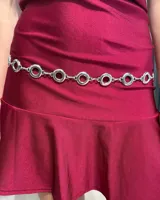 Cinturón de cadena plateada compuesto por eslabones circulares unidos entre sí, con un diseño minimalista y brillante.