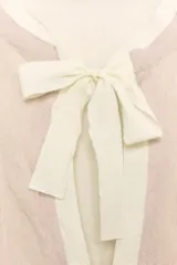 Chaqueta de punto color rosado con cuello redondo, manga larga y bolsillos delanteros. Presenta detalles de acabados con tejido combinado deshilachado en color blanco crudo y cierre frontal con lazos del mismo tono.