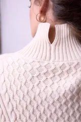 Sweater de punto color bordó con cuello alto y diseño de trenzas en el frente y las mangas. Presenta un corte holgado y largo, con puños y ruedo acanalados.