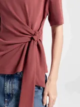 Blusa de algodón color beige, con cuello redondo, mangas cortas y detalle de lazo lateral que genera un efecto drapeado en la cintura.