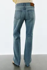 Jeans de tiro medio con corte slim y largo completo. Presentan diseño de cinco bolsillos, cierre frontal con cremallera y botón, efecto lavado y detalle de rotura en la parte delantera con bajo sin costura.