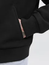 Campera bomber negra con cuello camisero, cierre frontal completo y bolsillos laterales, con puños y dobladillo acanalados.