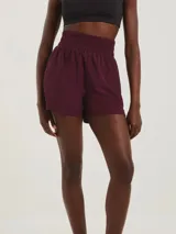 Short deportivo de corte runner con cintura elástica alta y fruncida, confeccionado en tejido técnico de secado rápido.