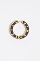 Aros tipo argolla metálicos en tono dorado con esmalte negro y letras grabadas en relieve con el nombre de la marca.