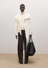 Blusa de seda color blanco marfil, con cuello alto drapeado y detalle de bufanda integrada al cuello. De manga larga con puños ajustados mediante tiras.