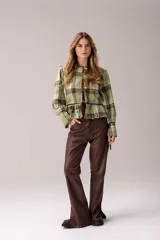 Blusa de manga larga confeccionada en tartán con estampado a cuadros en tonos marrones, blancos y mostaza. Presenta detalles en cuero marrón y cuello alto con corderito sintético.