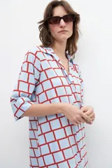 Maxi vestido camisero celeste con estampado geométrico de cuadrados rojos, mangas cortas y aberturas laterales.