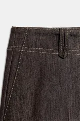 Pantalón de tiro medio en denim oscuro con costuras a contraste. Presenta corte recto, bolsillos delanteros, trabillas en la cintura y cierre frontal con cremallera y ganchos metálicos.